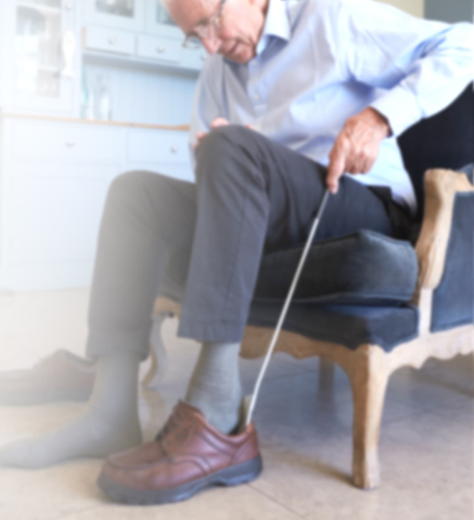 Das Bild zeigt einen sitzenden älteren Mann, der sich mit einem Schuhlöffel einen braunen Herrenschuh anzieht, der von Frank Kußmann in Mainz mit einer diabetes-adaptierten Fußbettung versorgt wurde.